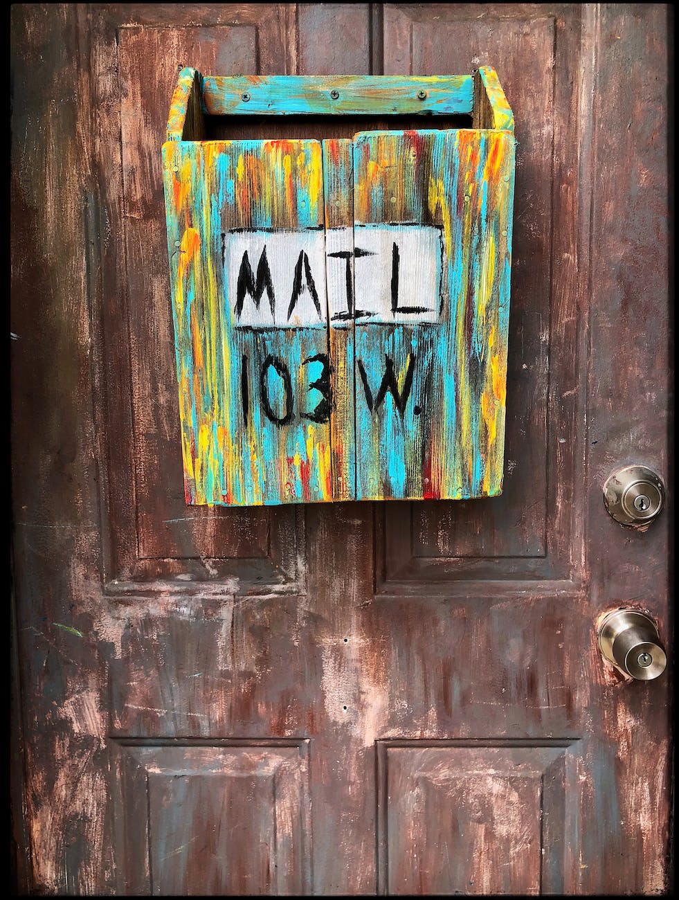 multi coloured wooden mailbox mounted on door